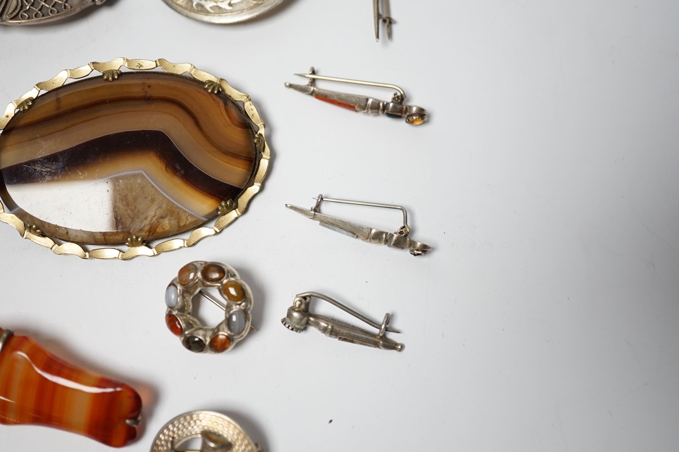 A small collection of mainly silver, sterling and white metal jewellery including Celtic brooches, Iona ship brooch, a Scottish hardstone set bugle brooch and other moss agate set and banded agate set items, largest broo